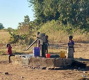 lil ones at a well getting water